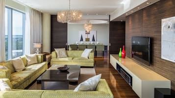 Een moderne woonkamer met een zithoek, een salontafel en een televisie op een witte dressoir.