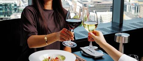 Una mesa de comedor con dos platos de comida, una copa de vino tinto y una copa de vino blanco.
