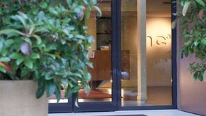 A hotel entrance with a glass door, a potted plant, and a visible interior with a reception area. - Hc3 Hotel (Bologna)