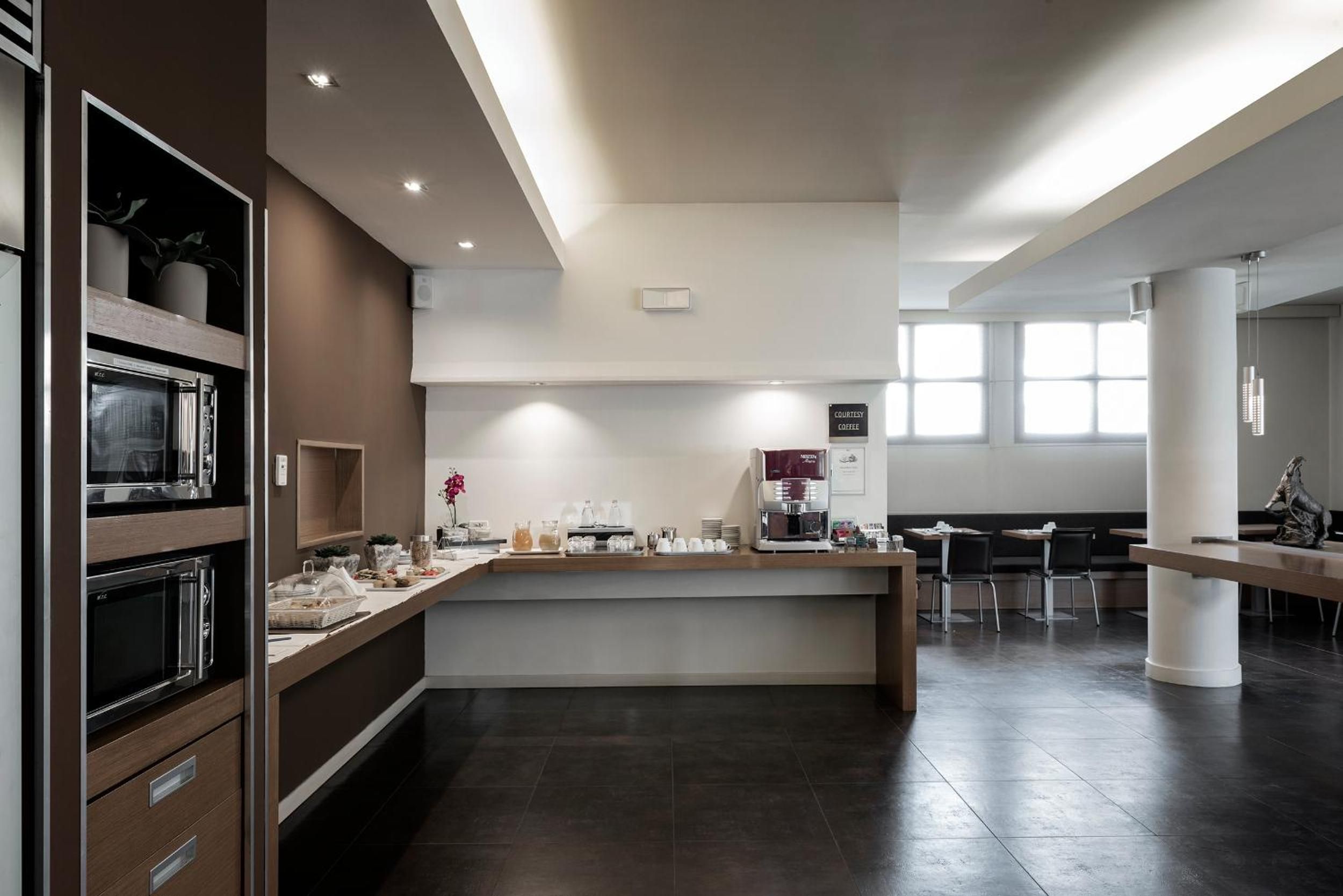 Een moderne keuken met inbouwapparatuur, een koffiehoek en een zithoek met tafels en stoelen.