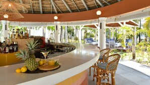 A bar area with a tropical theme, including a pineapple centerpiece, bar stools, and a thatched roof. - Veranda Belle Mare - All Inclusive (Belle Mare)