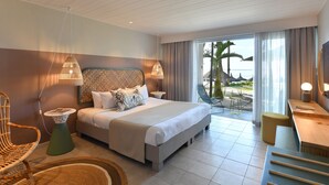 A modern hotel room with a large bed, a view of the beach, and a balcony with outdoor seating. - Veranda Belle Mare - All Inclusive (Belle Mare)