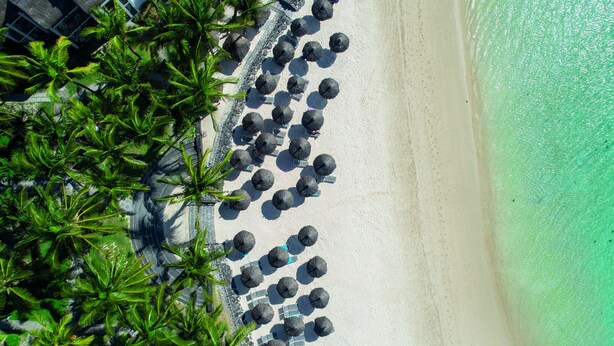 An aerial view of a beach with rows of umbrellas and palm trees. - Veranda Belle Mare - All Inclusive (Belle Mare)