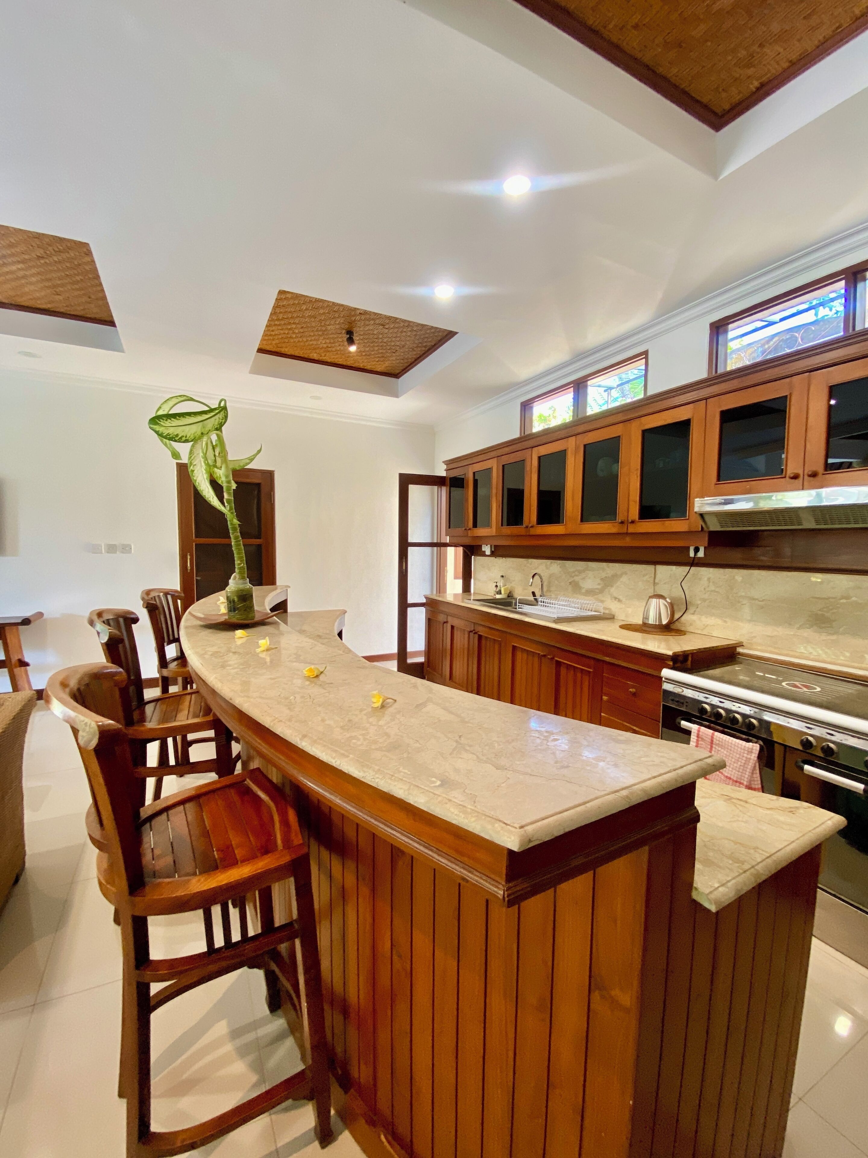 A kitchen with wooden cabinets, a marble countertop, and a stove.