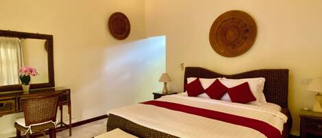 A bedroom with a bed, a ceiling fan, a mirror, a desk, and a chair.