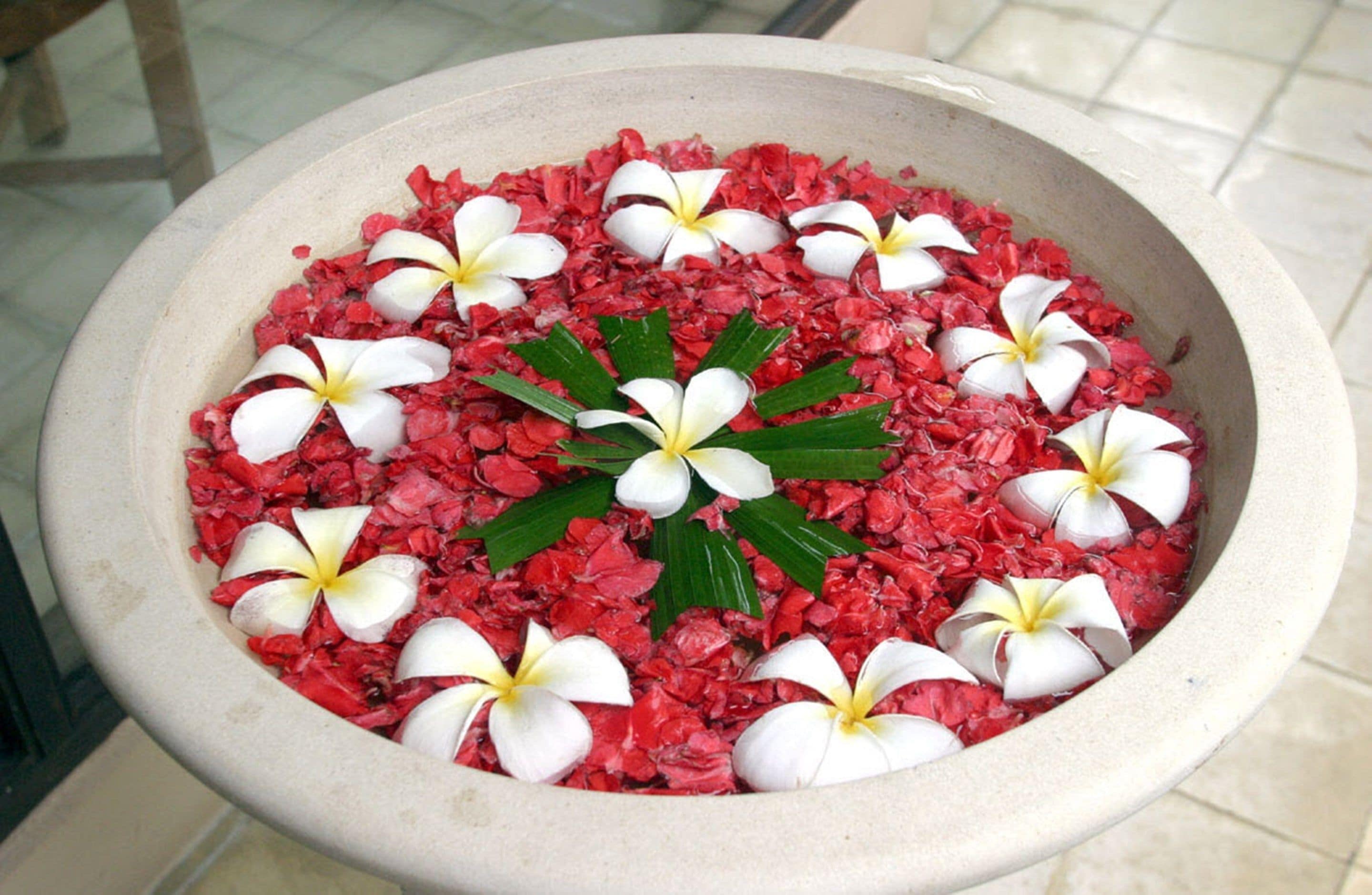 A stone basin filled with red pebbles and white flowers.