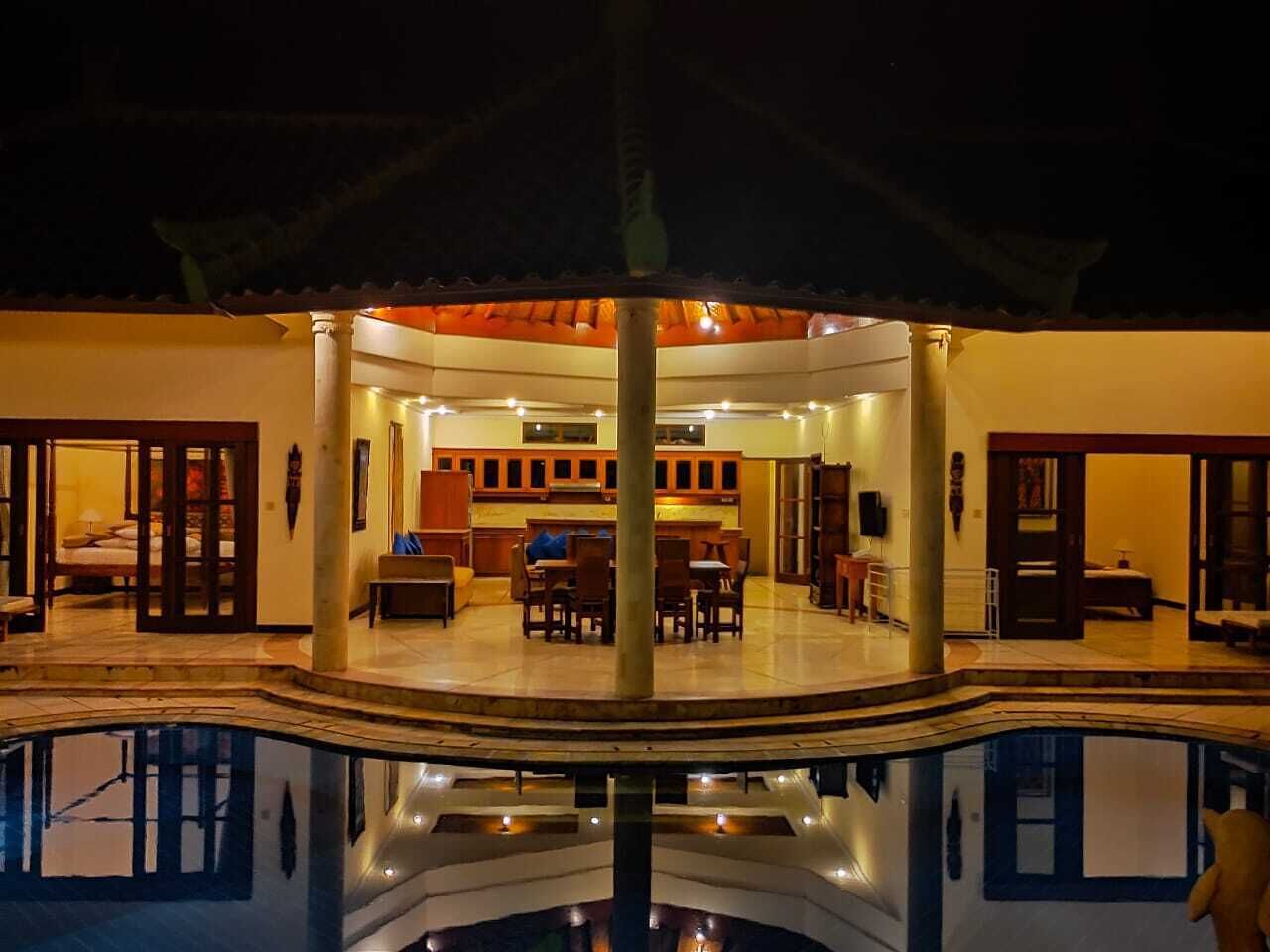A circular pool with a central column, surrounded by a covered seating area with tables and chairs.