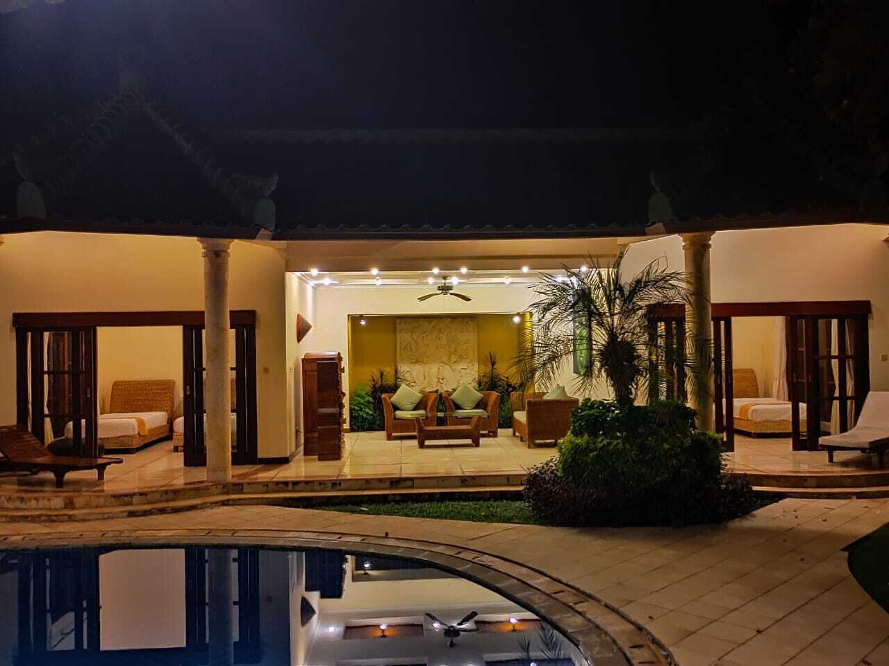 A poolside area with a lounge chair, a bed, and a ceiling fan.