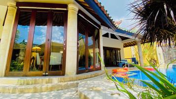 A building with large glass doors, a tiled patio, and a swimming pool.