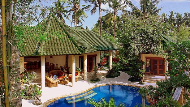 A poolside area with a covered seating area, a swimming pool, and tropical vegetation. - Bali Emerald Villas (Denpasar)