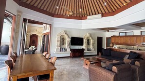 A spacious living area with a high ceiling, a dining table, sofas, and a TV. - Bali Emerald Villas (Denpasar)