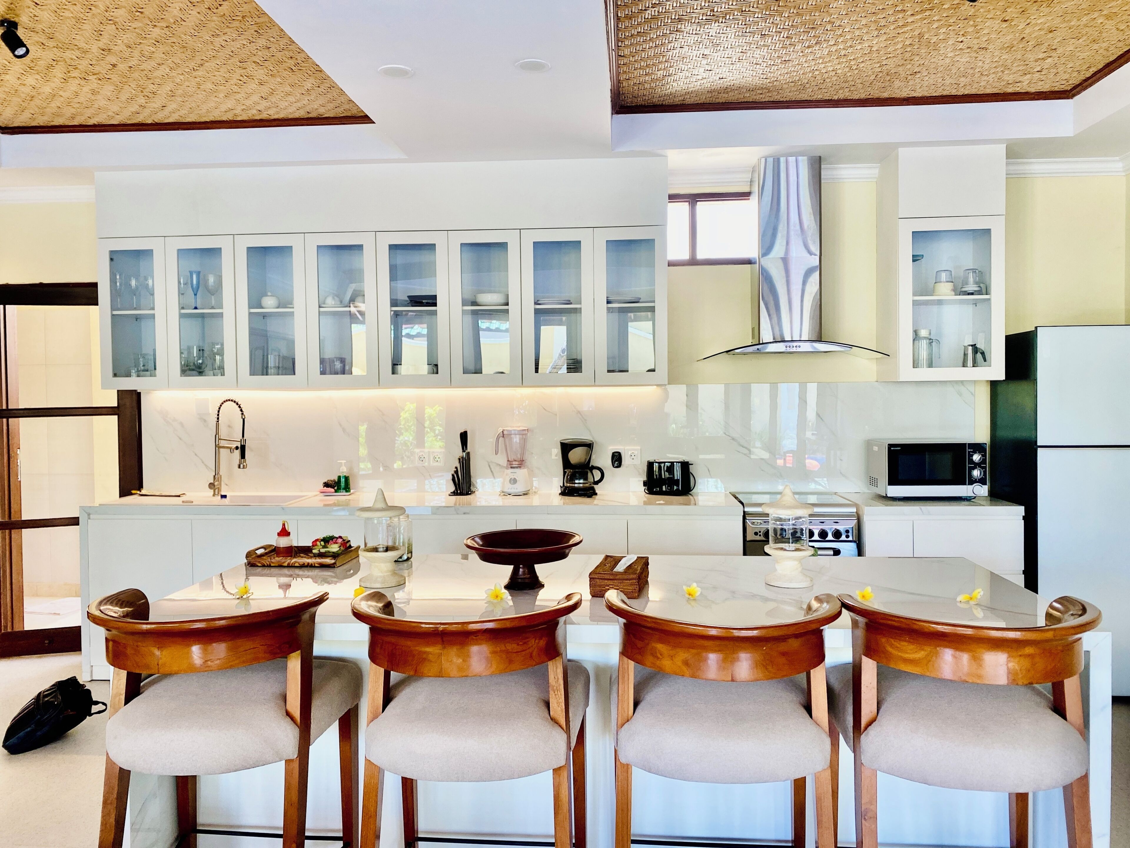 Une cuisine moderne avec des meubles blancs, un îlot central et des tabourets de bar.