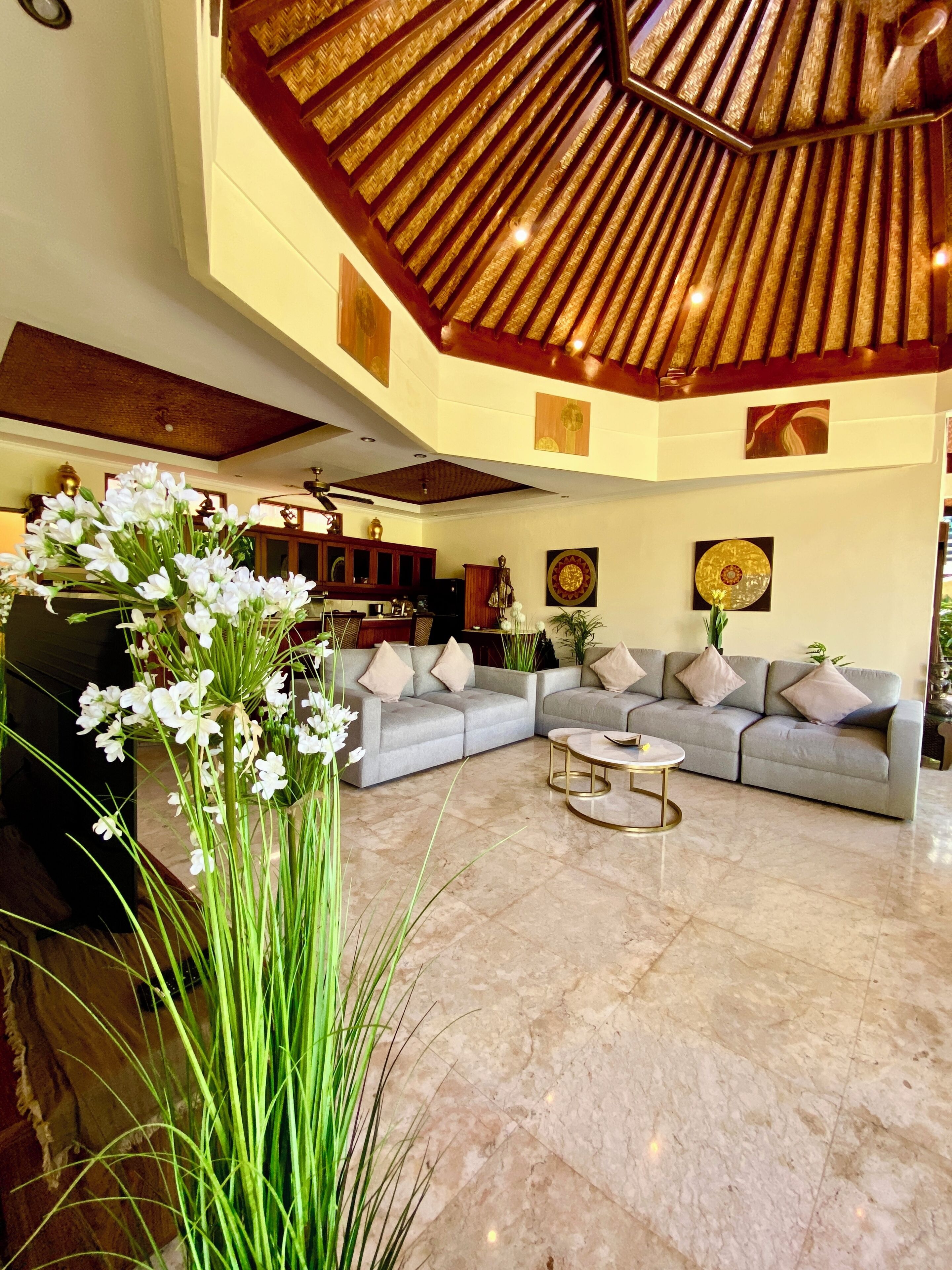 A spacious living area with a large sofa set, a coffee table, and a decorative plant.