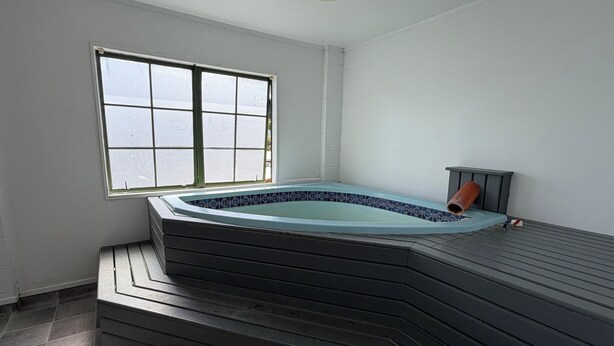 A hot tub with a tiled surround, a window, and a tiled floor. - Karaka Tree Motel (Taupo)