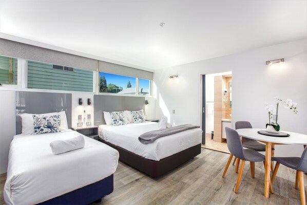 A modern hotel room with two beds, a dining area, and a view of the outdoors. - City Star Lodge (Kangaroo Point)