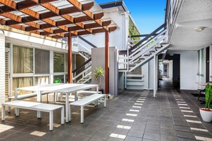 Un patio exterior con bancos blancos y una estructura de pérgola.