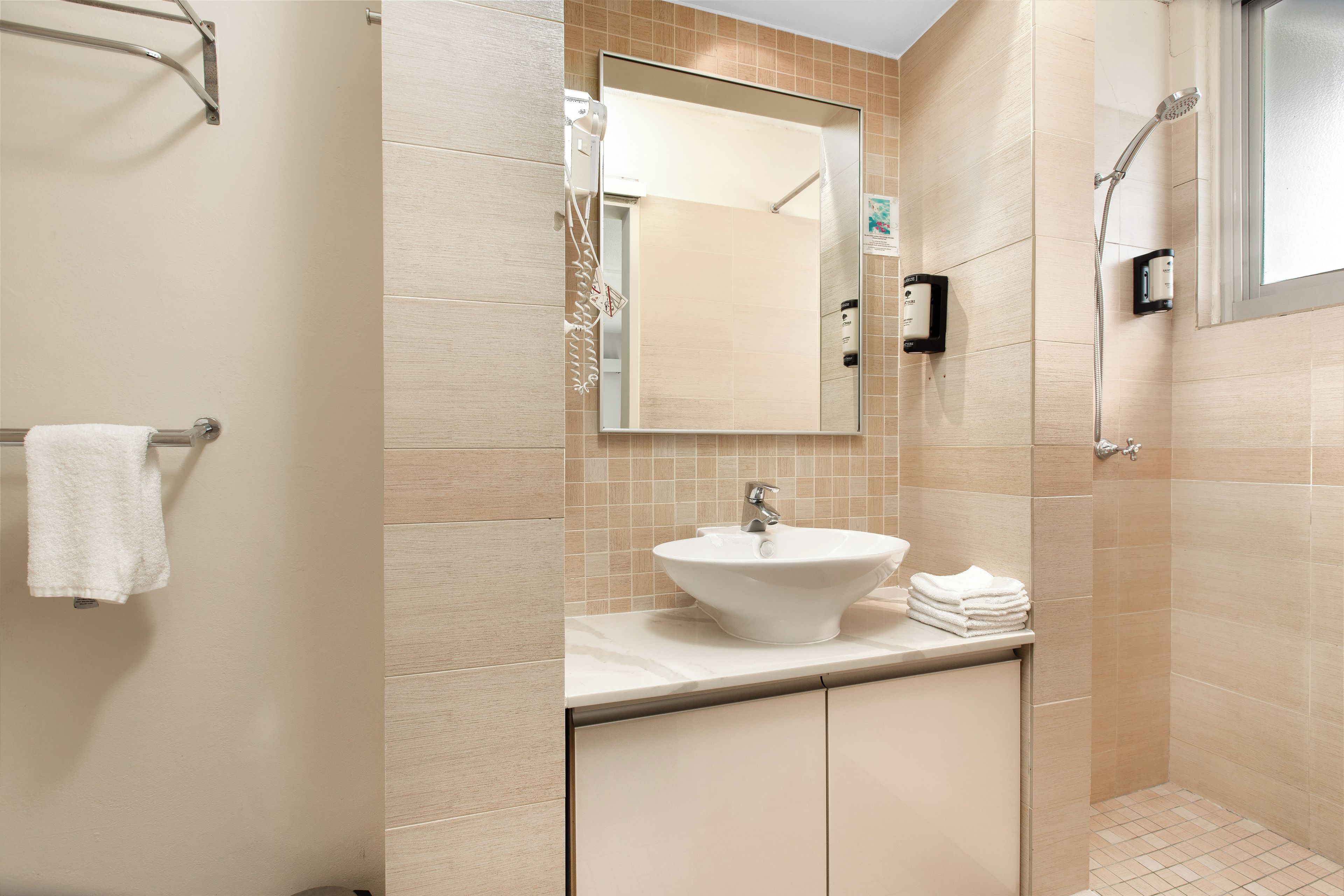 A bathroom with a sink, mirror, towel rack, and shower.
