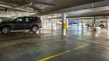 Un parking à plusieurs niveaux, avec des piliers en béton et des lignes jaunes peintes sur le sol.
