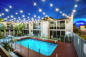 A modern hotel with a swimming pool, outdoor seating, and string lights. - City Star Lodge (Kangaroo Point)