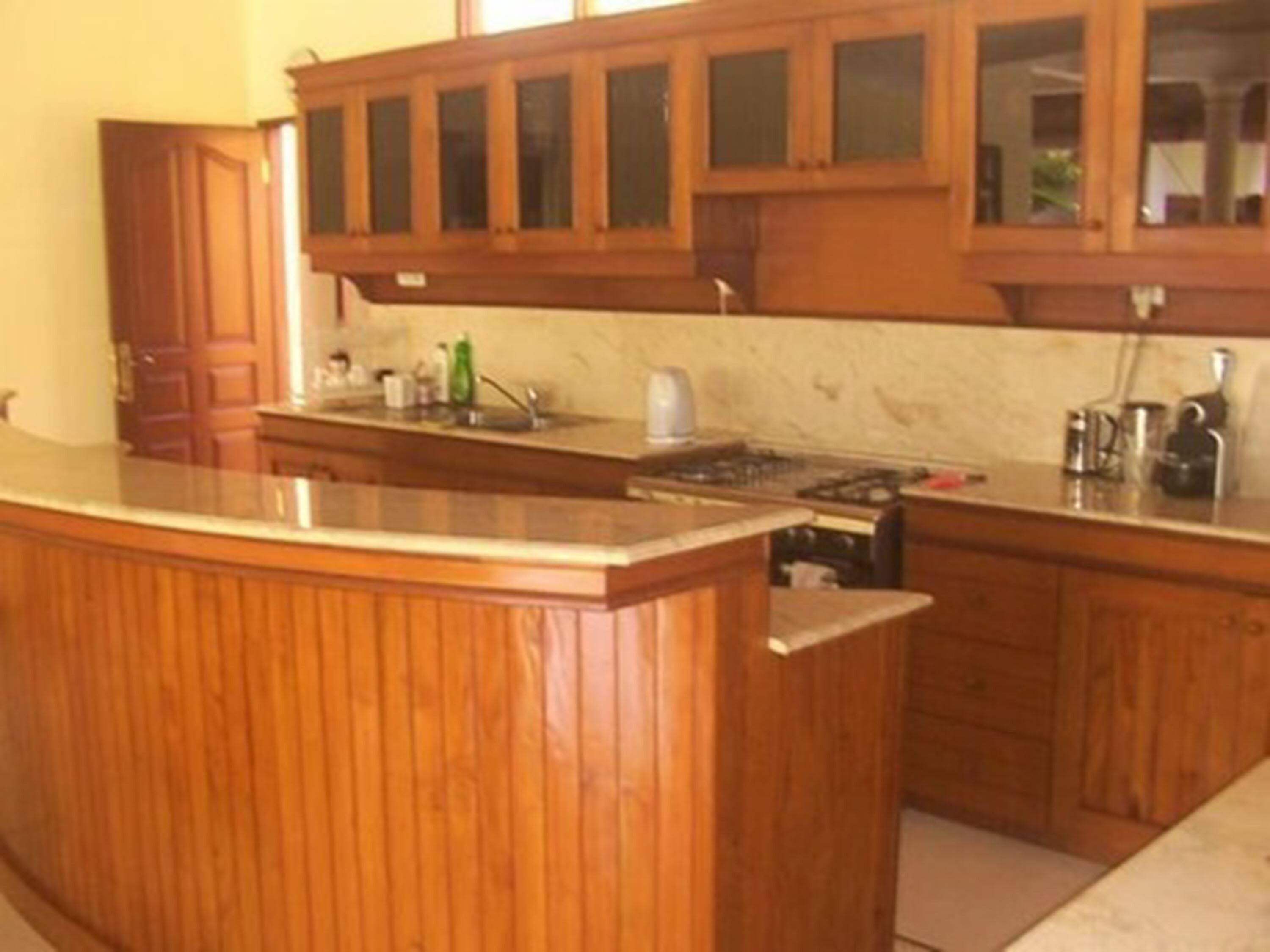 Una cocina con armarios de madera, encimera de mármol y una estufa.