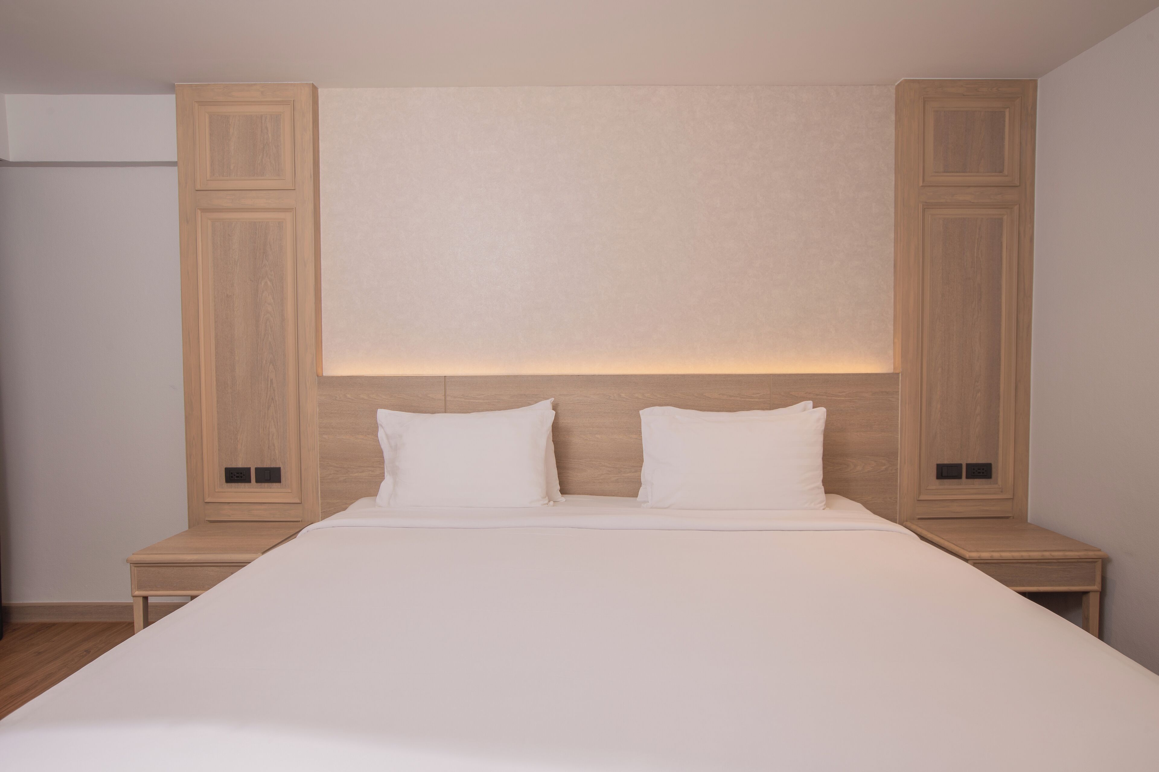Ein modernes Schlafzimmer mit einem großen Bett, einem Holzkopfteil und Nachttischen.