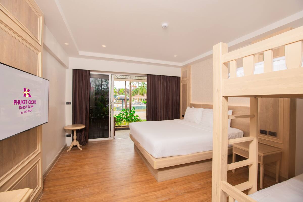 A hotel room with a bed, a desk, a TV, and a view of the outdoors.