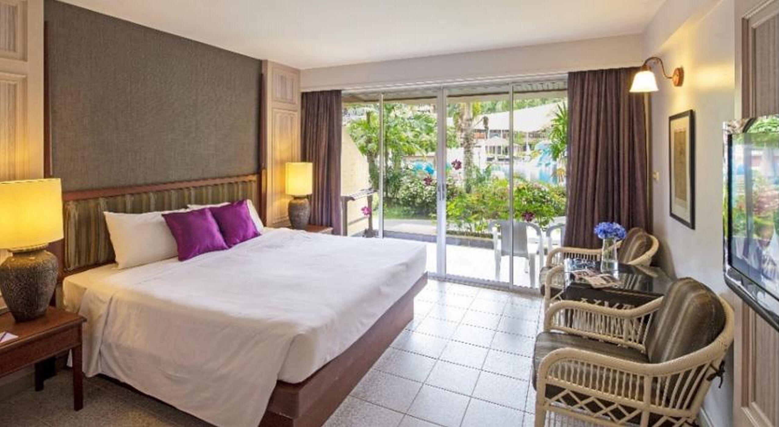 A hotel room with a large bed, a desk, a chair, and a view of the outdoors.