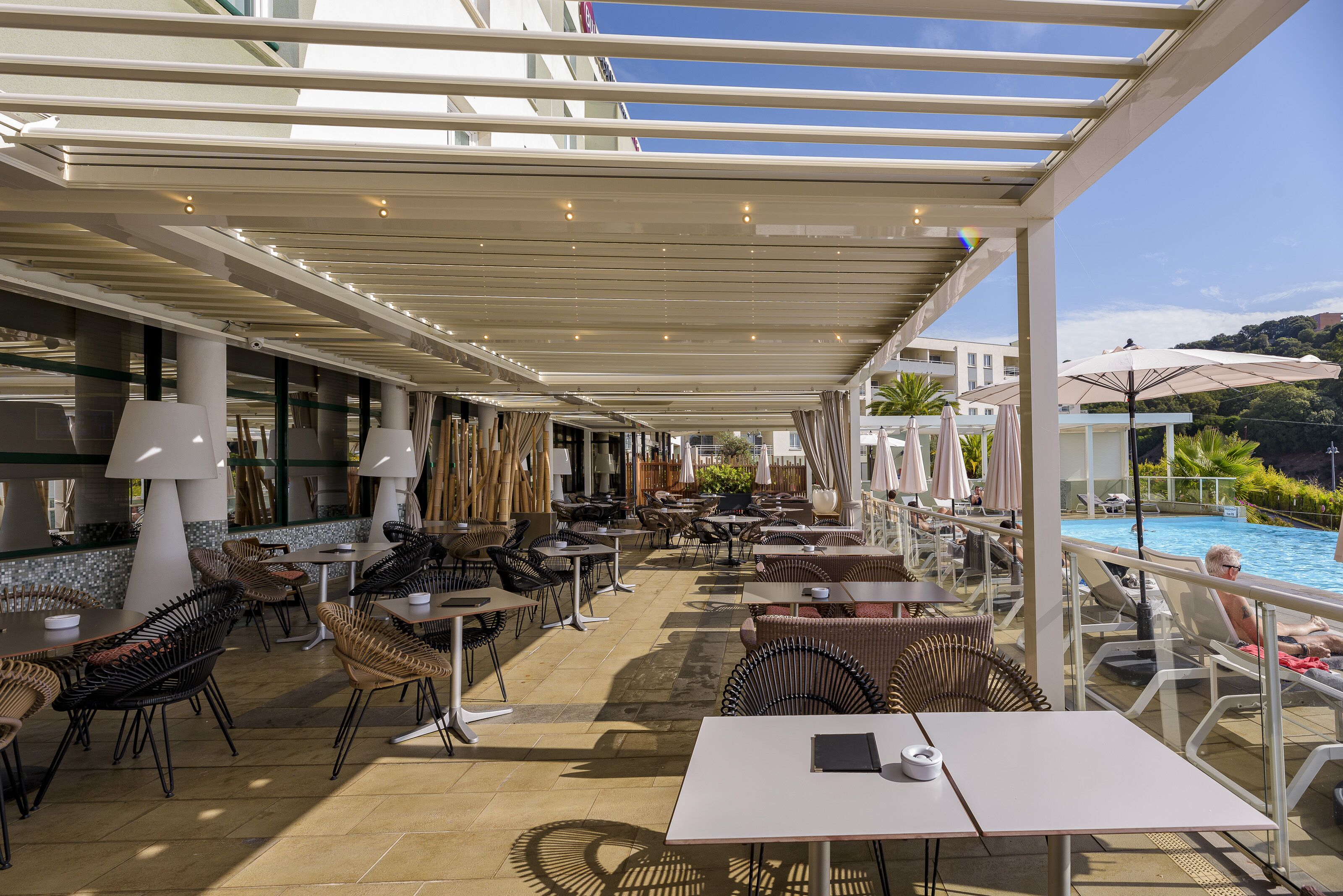 Un espace extérieur aménagé avec des tables, des chaises, une piscine et des parasols.