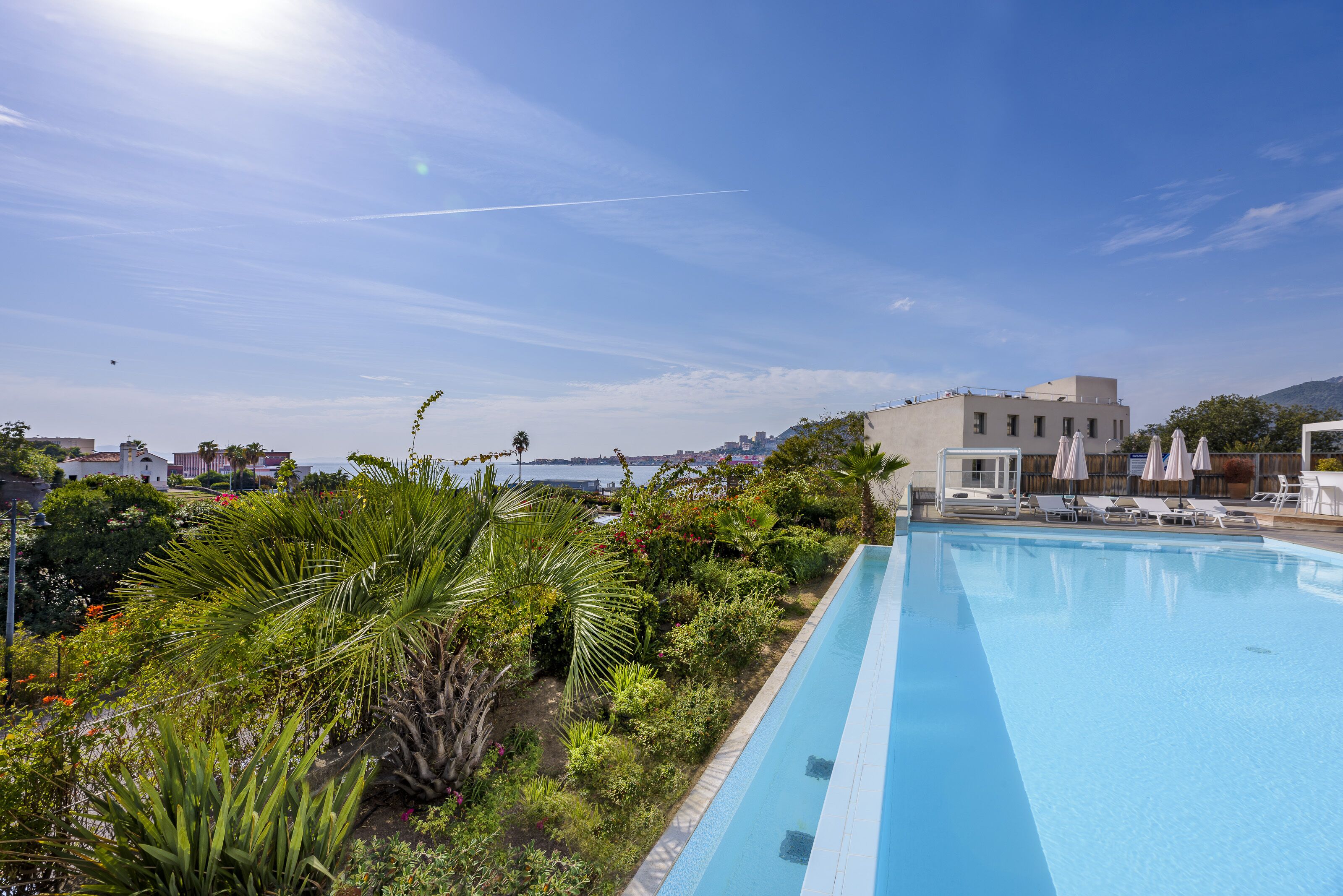 Une piscine offrant une vue dégagée sur la mer, avec un bâtiment visible à l’arrière-plan.