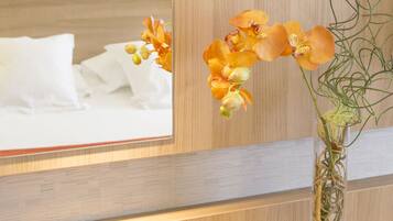 Ein Badezimmer mit einem Holzkosmetikschrank, einem Spiegel und einer Vase mit Blumen.