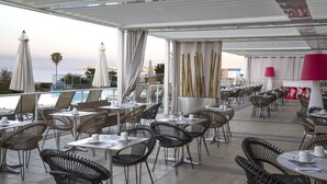An outdoor dining area with tables and chairs, overlooking a pool and the ocean. - Best Western Plus Ajaccio Amiraute (Ajaccio)