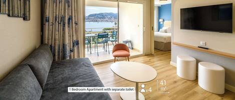 A 1-bedroom apartment with a separate toilet, a balcony with a view, a flat-screen TV, and a small dining area.