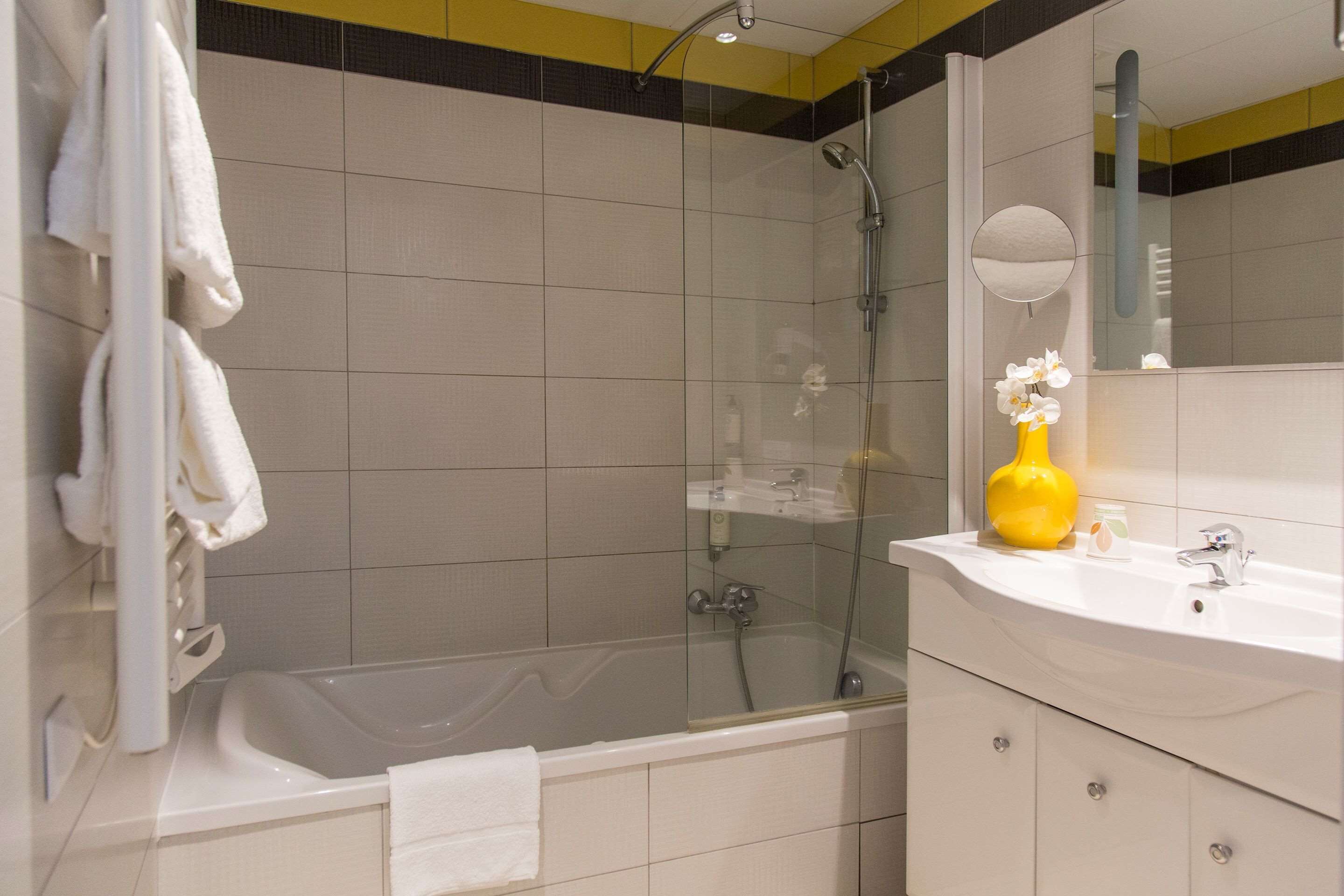 A modern bathroom with a bathtub, a glass-enclosed shower, and a white vanity with a mirror.