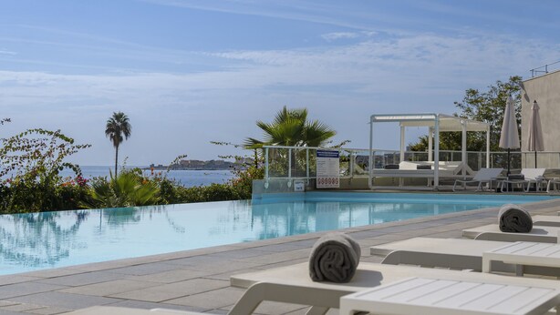A pool area with lounge chairs, a covered seating area, and a view of the sea. - Best Western Plus Ajaccio Amiraute (Ajaccio)