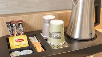 A coffee station with a kettle, cups, and coffee pods.
