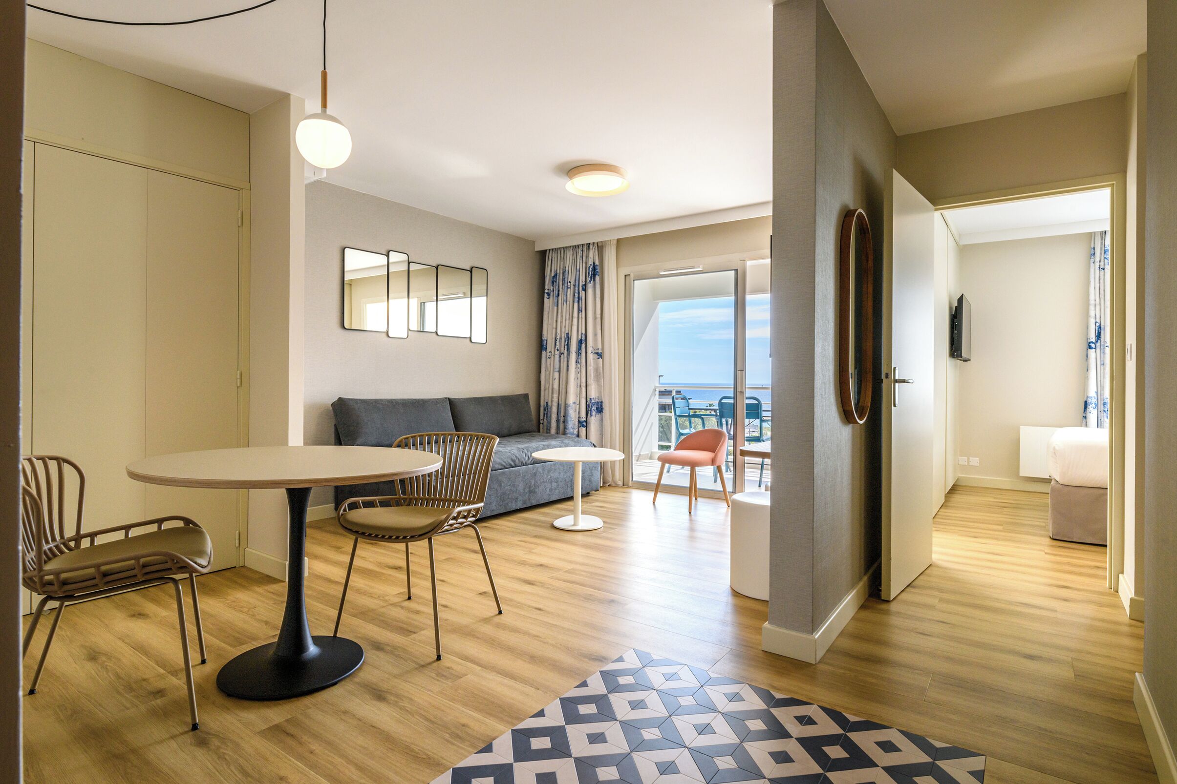 Una sala de estar moderna con una mesa redonda, dos sillones, un sofá y vistas a la ciudad.