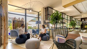 A modern lounge area with seating, a large plant, and a view of the cityscape. - Best Western Plus Ajaccio Amiraute (Ajaccio)