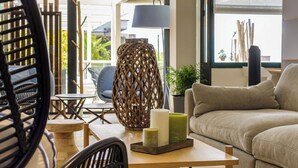 A modern living room with a sofa, a wooden coffee table, a wicker lamp, and a view of the outdoors. - Best Western Plus Ajaccio Amiraute (Ajaccio)