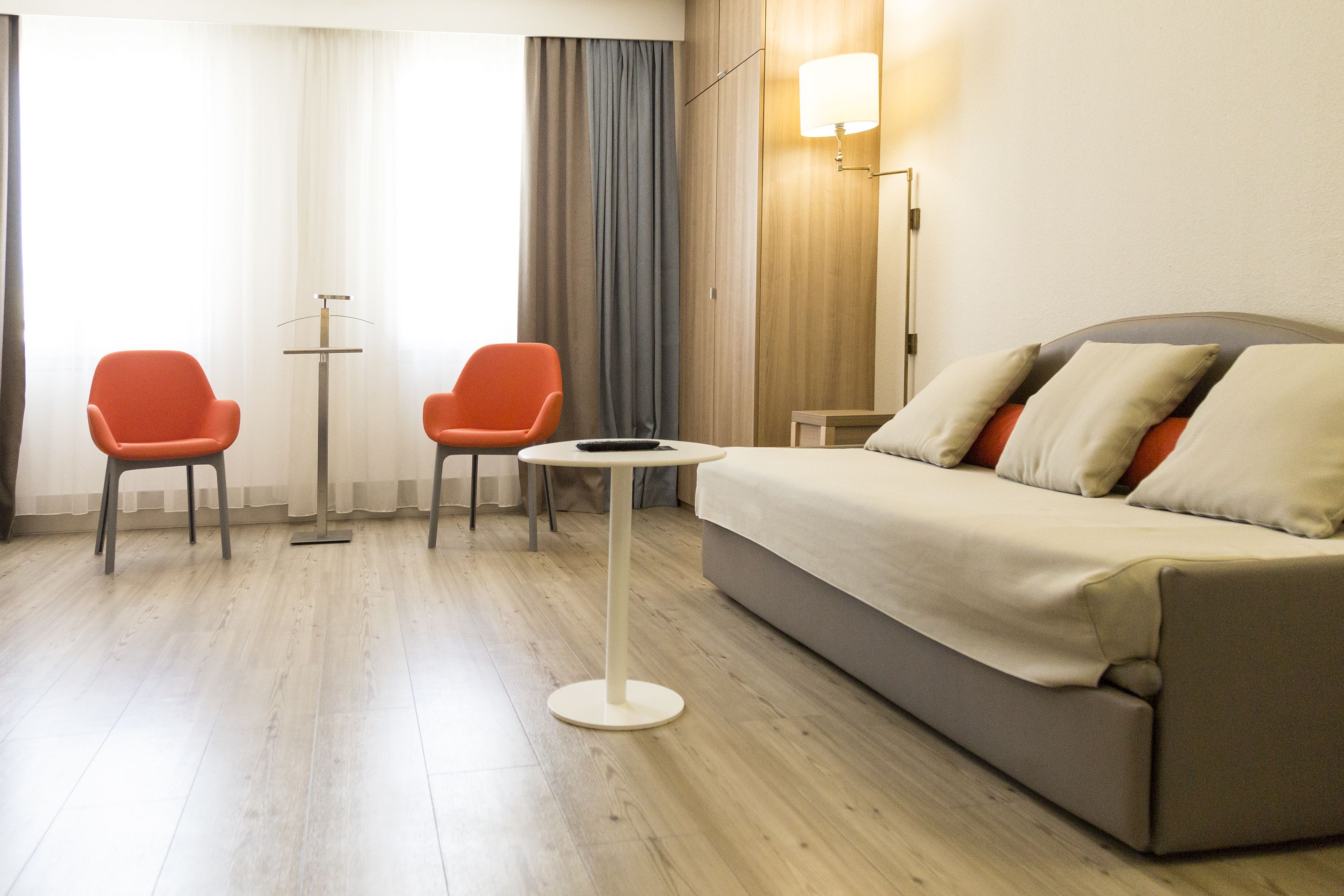 Habitación de hotel con sofá, dos sillones, una mesita redonda y una lámpara de pie.