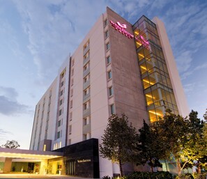 A high-rise hotel with a prominent pink sign, multiple balconies, and a modern architectural design.