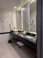 Un baño moderno con dos lavamanos, un espejo grande y un banco con toallas.