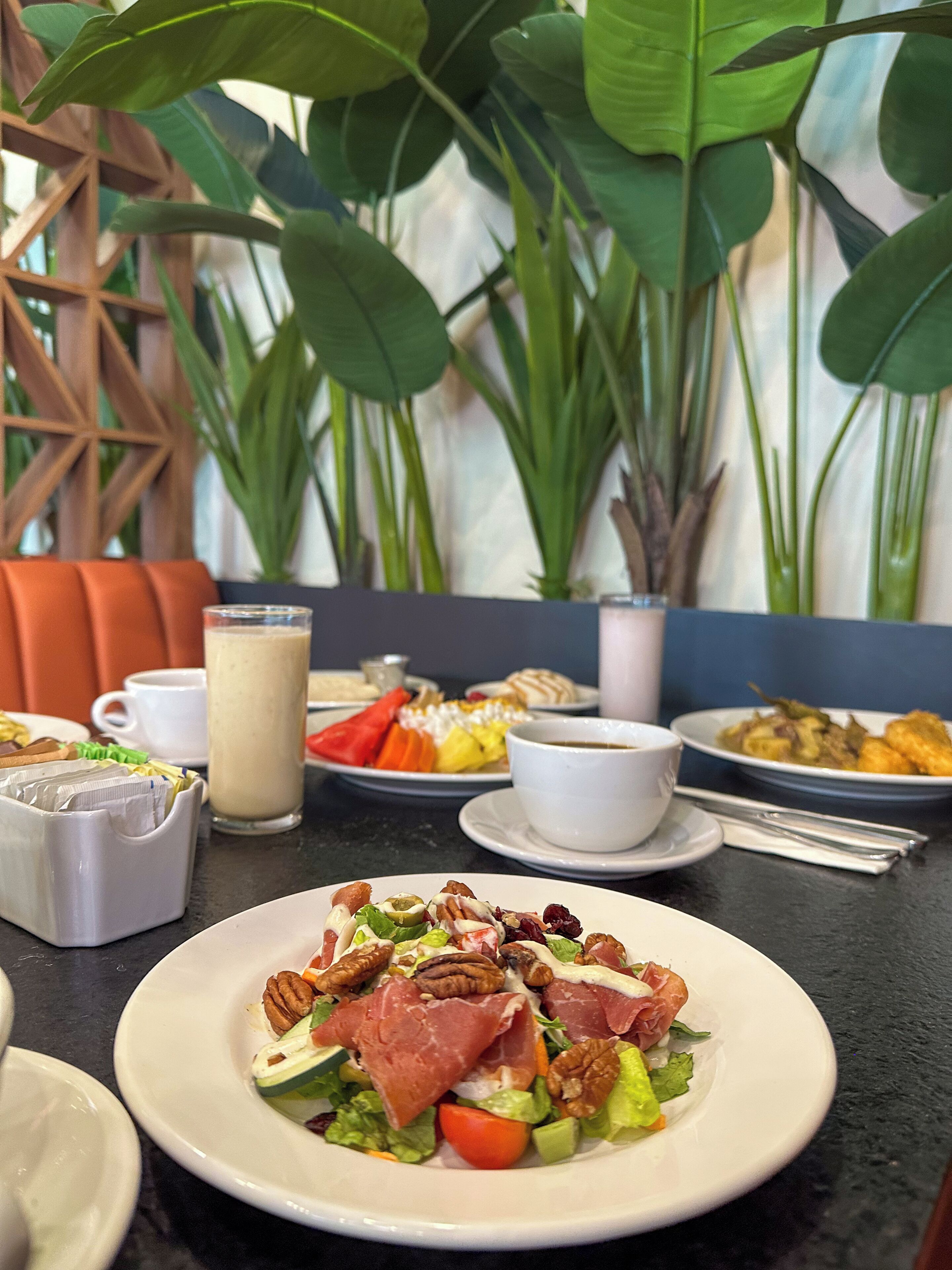 Une table à manger avec différents plats, notamment une salade aux noix et à la viande, et un verre de lait.