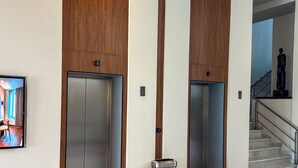 Eine moderne Lobby mit zwei Aufzügen, einem Marmorboden und einer Treppe.