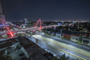 Un paisaje urbano nocturno con un puente iluminado en rojo y una autopista.