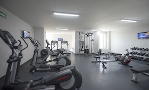 Un gimnasio con cintas de correr, elípticas, máquinas de pesas y mancuernas.