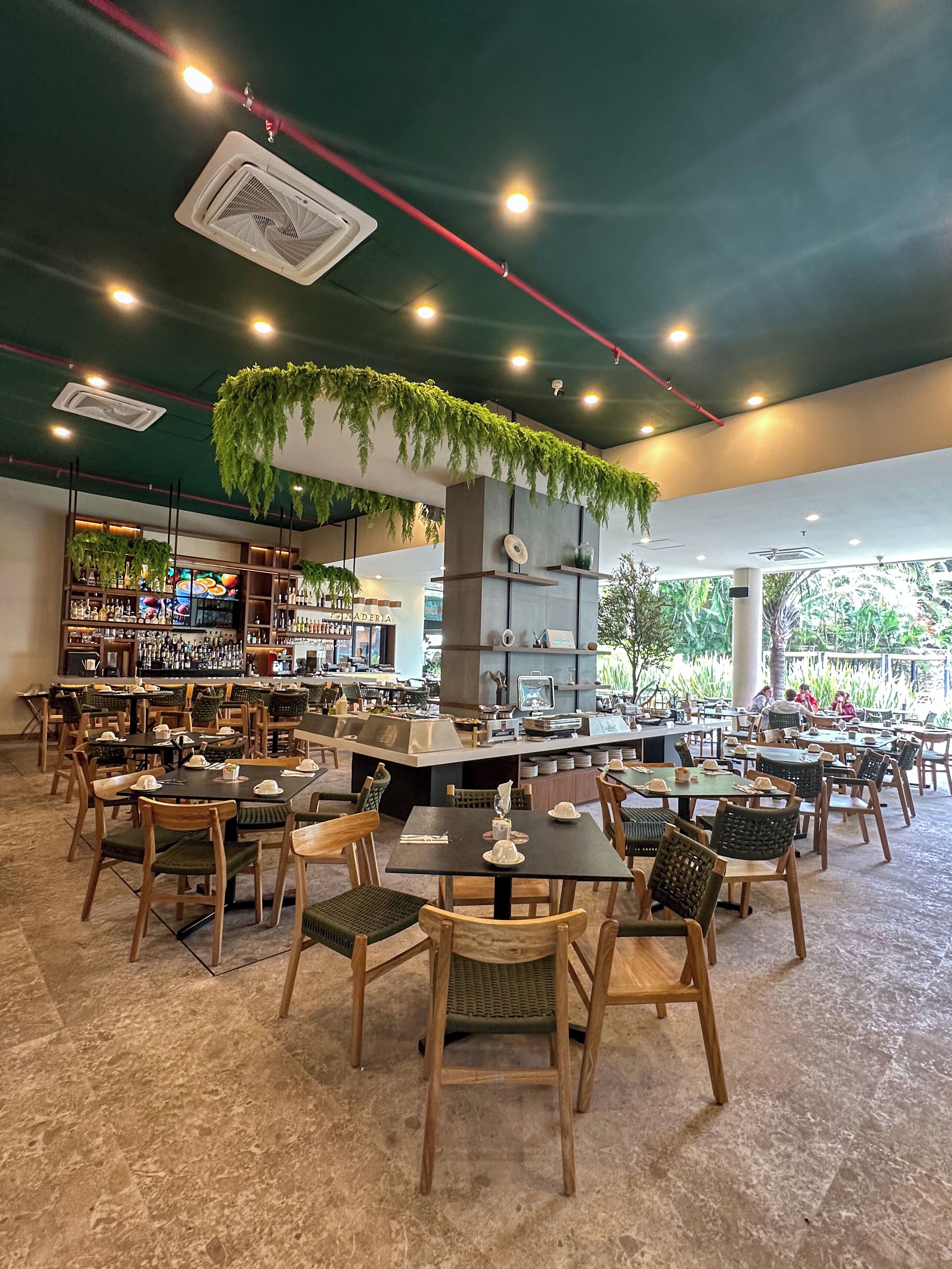 Een restaurant met binnenzitplaatsen, een bar en een plafond met hangplanten.