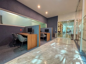 Un espacio de oficina moderno con cubículos, escritorios, sillas y un muro de vidrio.