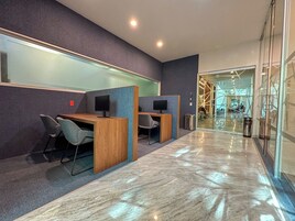 Un espacio de oficina moderno con cubículos, escritorios, sillas y un muro de vidrio.
