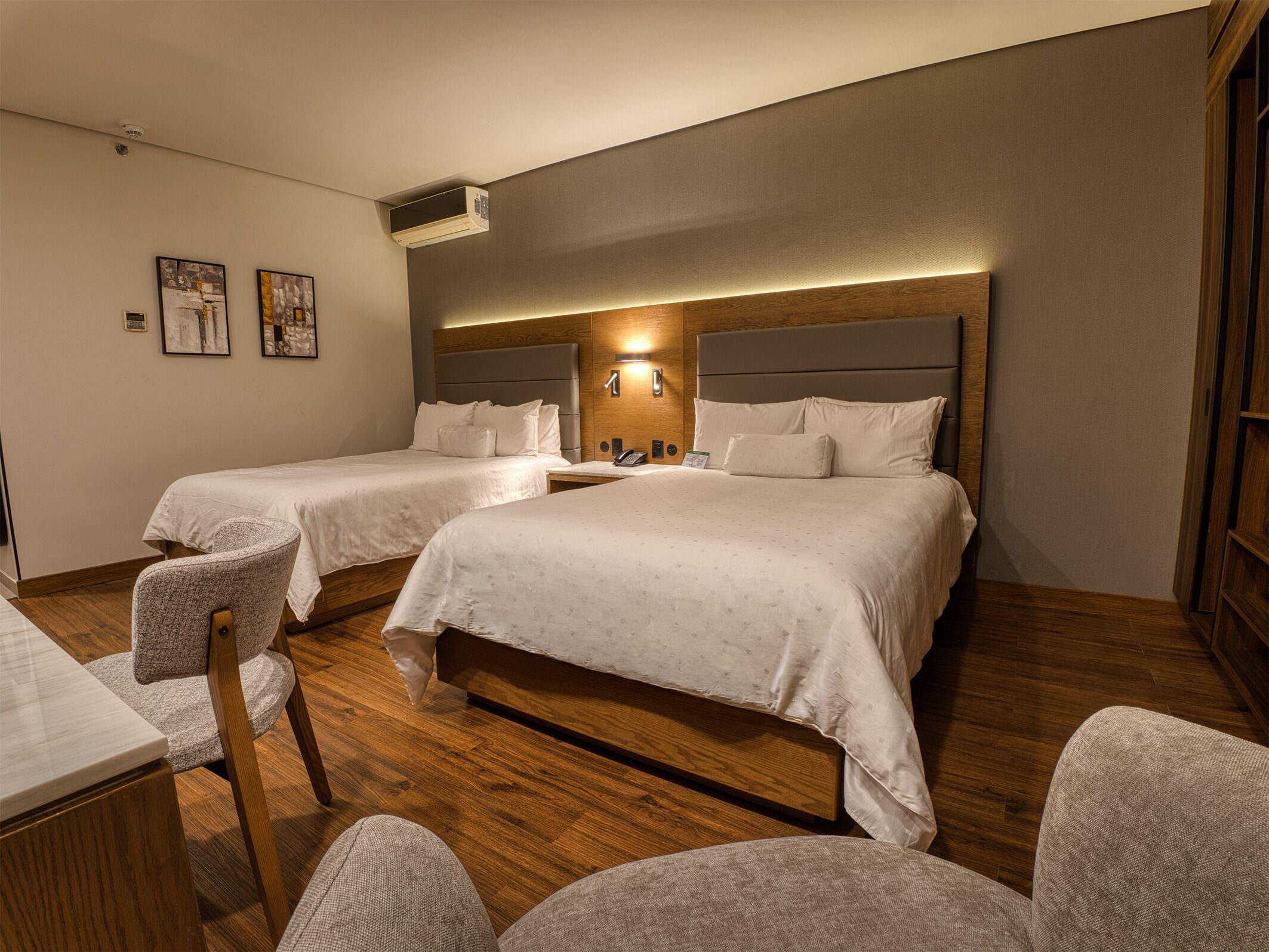 Habitación de hotel con dos camas, un escritorio y una silla.