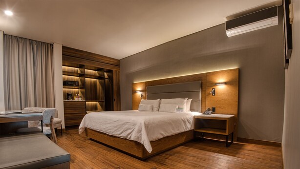 Une chambre d’hôtel moderne dotée d’un grand lit, d’un bureau et d’une armoire intégrée.